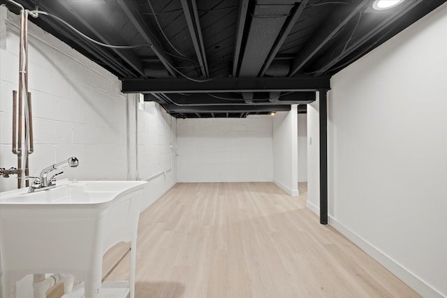 basement with light wood-type flooring and sink