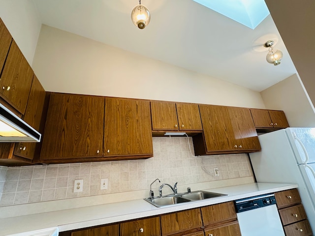 kitchen with backsplash, vaulted ceiling with skylight, white appliances, sink, and range hood