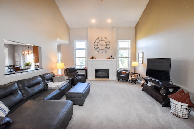 carpeted living room featuring a towering ceiling and a notable chandelier