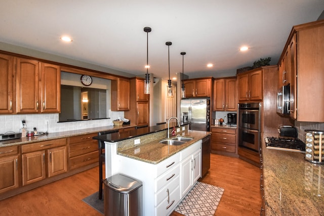 kitchen with decorative light fixtures, light wood-type flooring, sink, and stainless steel appliances