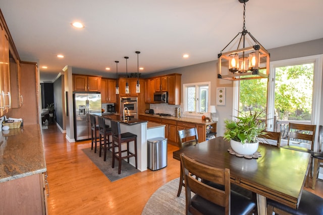 dining room with a notable chandelier, plenty of natural light, and light hardwood / wood-style floors