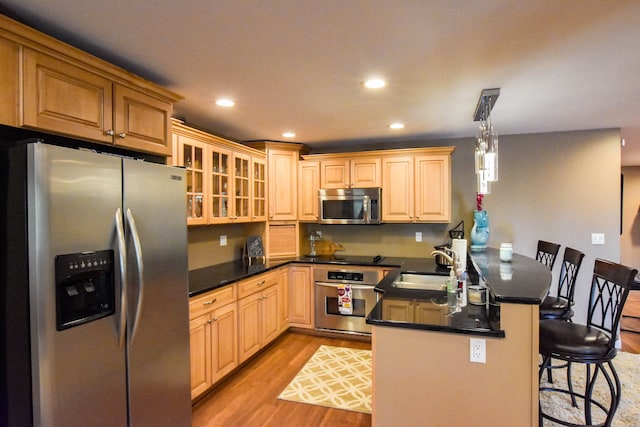 kitchen featuring a kitchen breakfast bar, sink, hanging light fixtures, appliances with stainless steel finishes, and kitchen peninsula