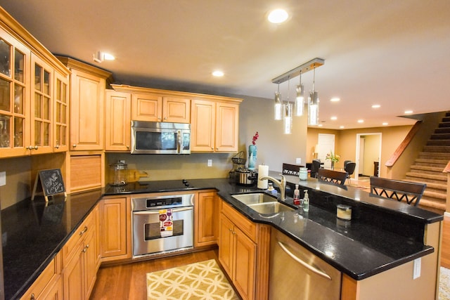 kitchen featuring sink, light hardwood / wood-style flooring, decorative light fixtures, a kitchen bar, and stainless steel appliances