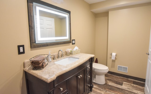 bathroom with wood-type flooring, vanity, and toilet