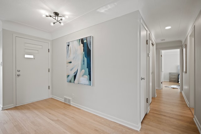 foyer featuring an inviting chandelier and light hardwood / wood-style flooring