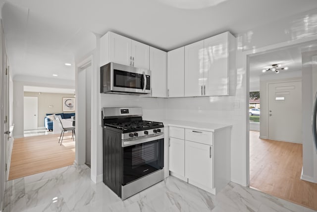 kitchen with backsplash, white cabinetry, and stainless steel appliances