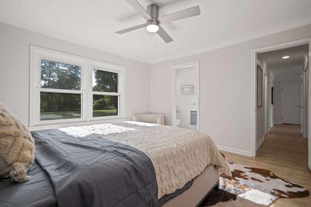 bedroom featuring ceiling fan, ensuite bath, and light hardwood / wood-style flooring