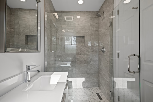 bathroom featuring a shower with door and vanity