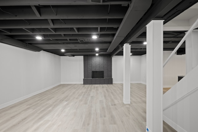 basement featuring a fireplace and light hardwood / wood-style floors