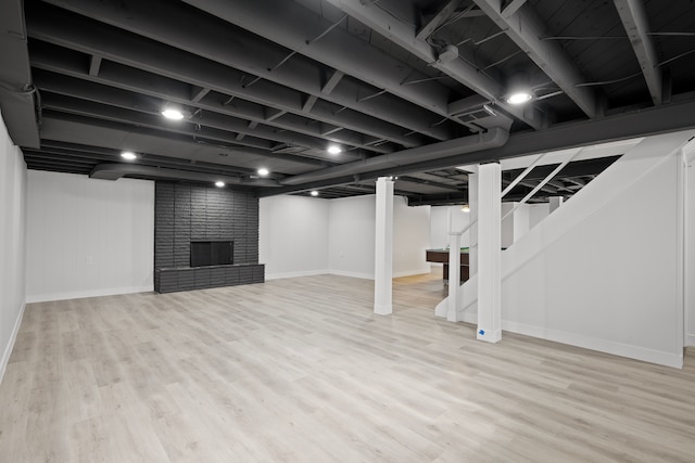 basement with a fireplace and light wood-type flooring