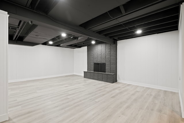 basement with a fireplace and light hardwood / wood-style floors