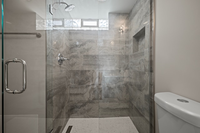 bathroom featuring a shower with shower door and toilet