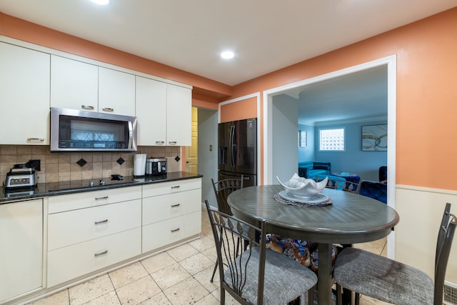 kitchen featuring white cabinets, backsplash, and black appliances