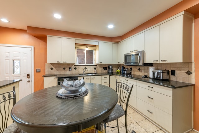 kitchen with tasteful backsplash, sink, white cabinets, and black appliances