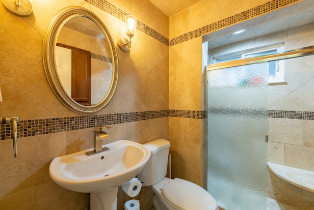 bathroom featuring tasteful backsplash, a shower with door, sink, tile walls, and toilet