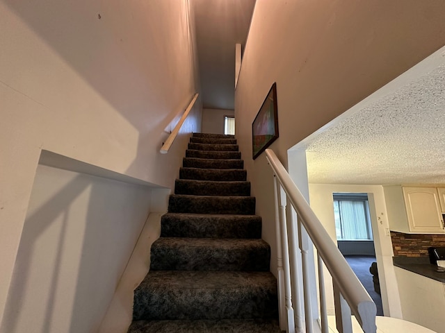 staircase featuring a textured ceiling