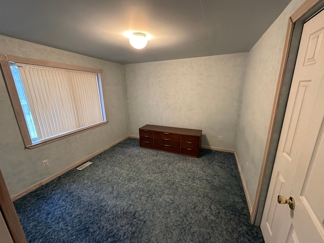 spare room featuring dark carpet