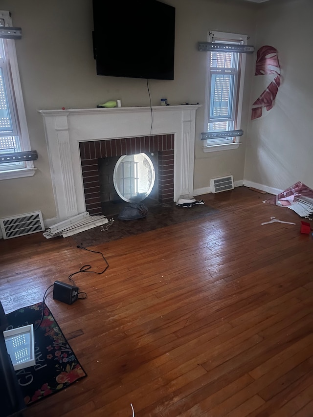 unfurnished living room featuring dark hardwood / wood-style flooring and a brick fireplace