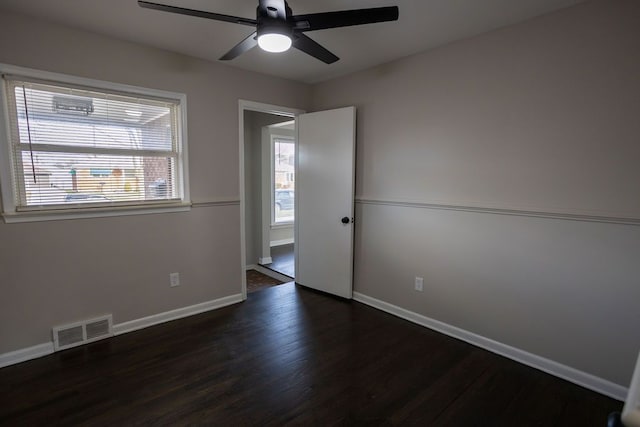 unfurnished room featuring a wealth of natural light, dark wood-type flooring, and ceiling fan