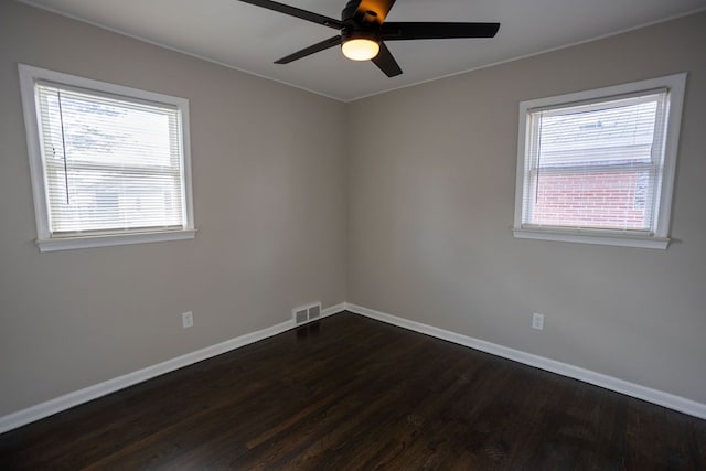 spare room featuring a wealth of natural light, ceiling fan, and dark wood-type flooring