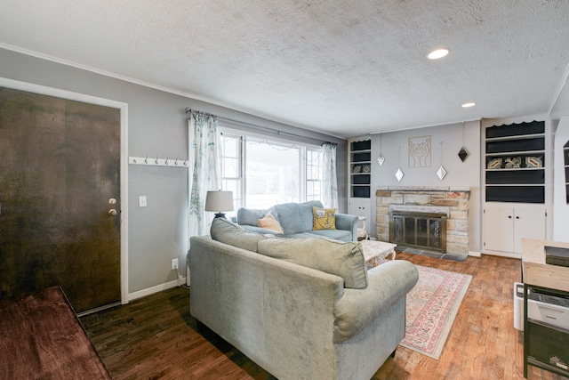 living room featuring built in shelves, a fireplace, a textured ceiling, and hardwood / wood-style flooring