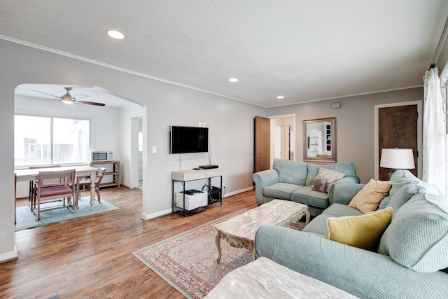 living room with a textured ceiling, light hardwood / wood-style floors, ceiling fan, and crown molding