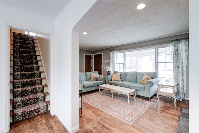 living room with wood-type flooring, a textured ceiling, and ornamental molding