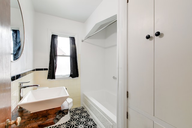 bathroom with sink, shower / washtub combination, and tile walls