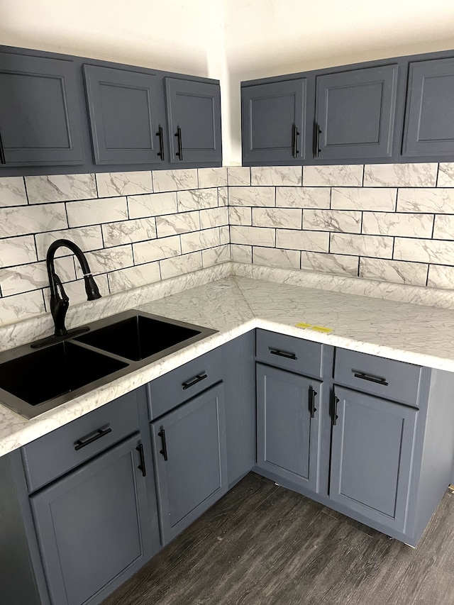 kitchen with light stone counters, dark hardwood / wood-style flooring, gray cabinets, and sink