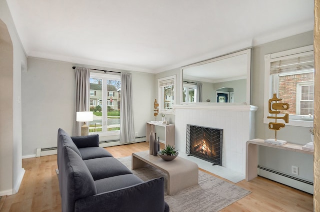 living room featuring ornamental molding, light wood-type flooring, and a baseboard heating unit