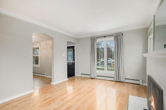 unfurnished living room featuring hardwood / wood-style floors, crown molding, a baseboard heating unit, and a tiled fireplace