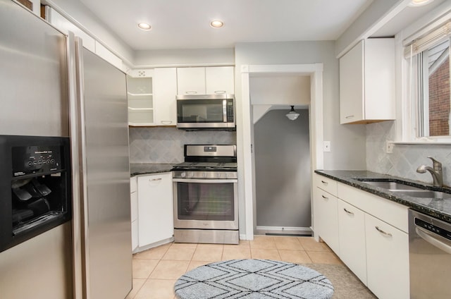 kitchen featuring sink, stainless steel appliances, white cabinets, dark stone countertops, and light tile patterned flooring