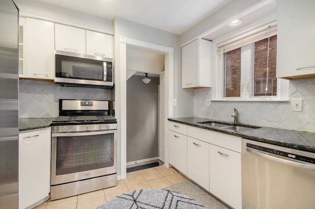 kitchen with white cabinets, stainless steel appliances, dark stone countertops, and sink