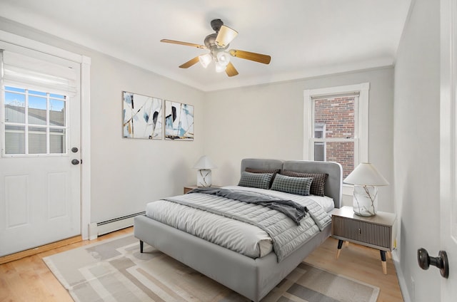 bedroom featuring ceiling fan, light hardwood / wood-style floors, ornamental molding, and a baseboard radiator