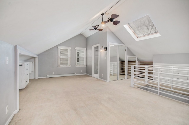 additional living space with vaulted ceiling with skylight, ceiling fan, light carpet, and a baseboard radiator