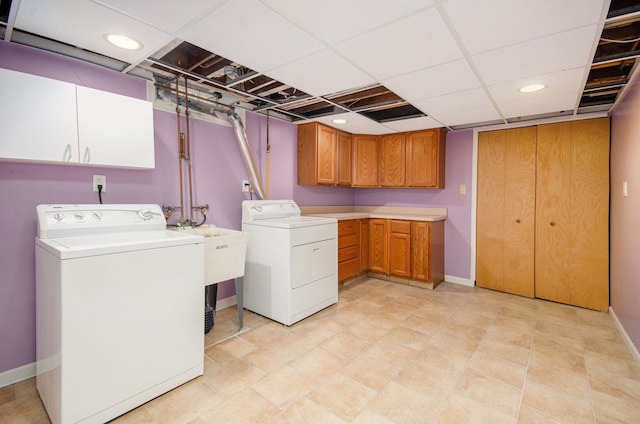 clothes washing area with washer and clothes dryer and cabinets