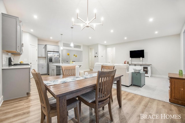 dining room with a notable chandelier, sink, and light hardwood / wood-style flooring