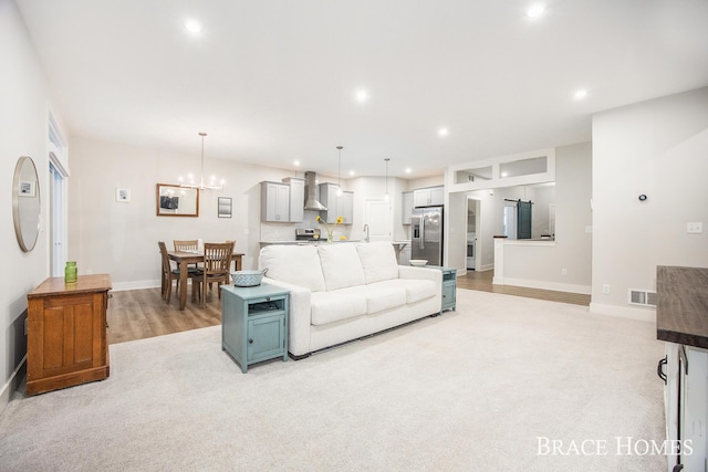 carpeted living room featuring an inviting chandelier and sink