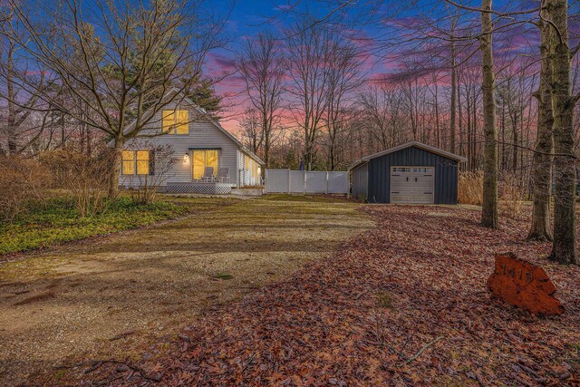 yard at dusk featuring a garage and an outdoor structure