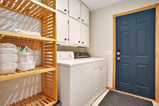 laundry area with light tile patterned flooring, cabinets, and washing machine and clothes dryer