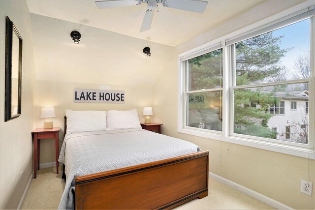 bedroom with ceiling fan, light colored carpet, and vaulted ceiling