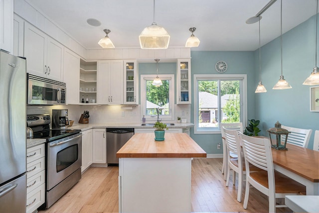 kitchen featuring white cabinets, decorative light fixtures, stainless steel appliances, and a kitchen island