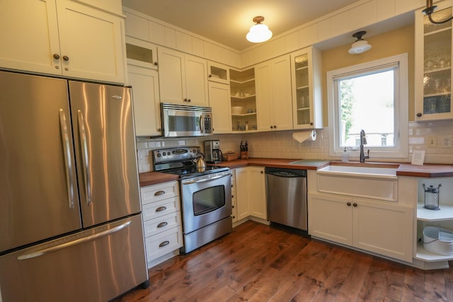 kitchen with dark hardwood / wood-style floors, decorative backsplash, white cabinetry, and stainless steel appliances