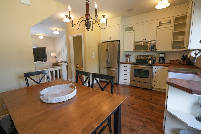 kitchen with appliances with stainless steel finishes, backsplash, white cabinetry, and a notable chandelier