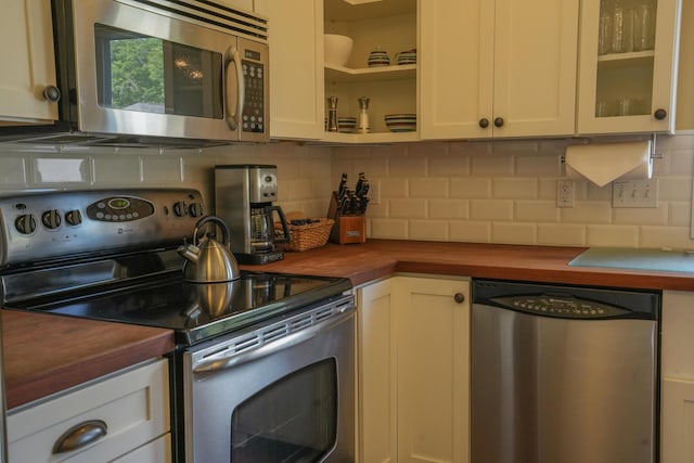 kitchen featuring butcher block countertops, white cabinetry, backsplash, and appliances with stainless steel finishes