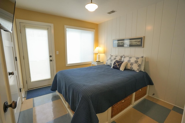 bedroom with multiple windows and wooden walls