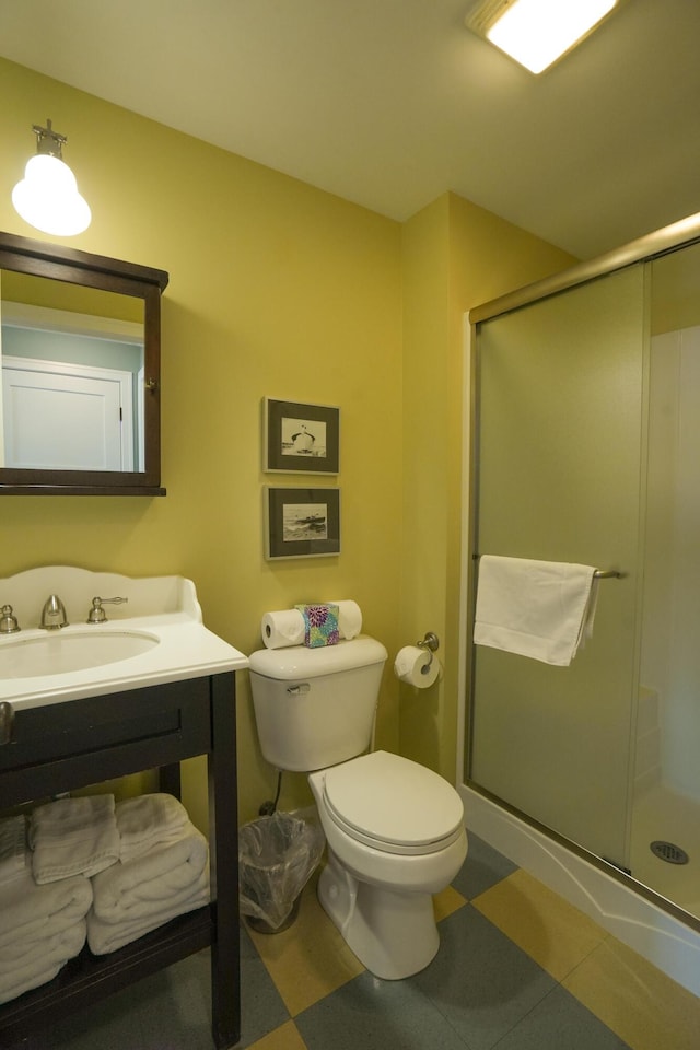 bathroom featuring toilet, a shower with door, and sink