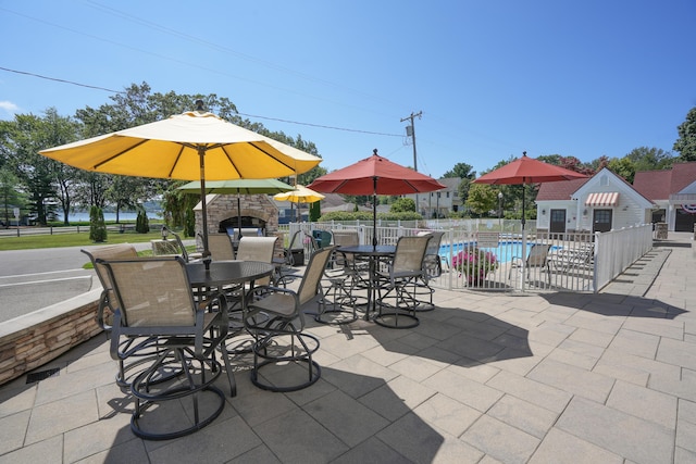 view of patio with an outdoor stone fireplace and a fenced in pool