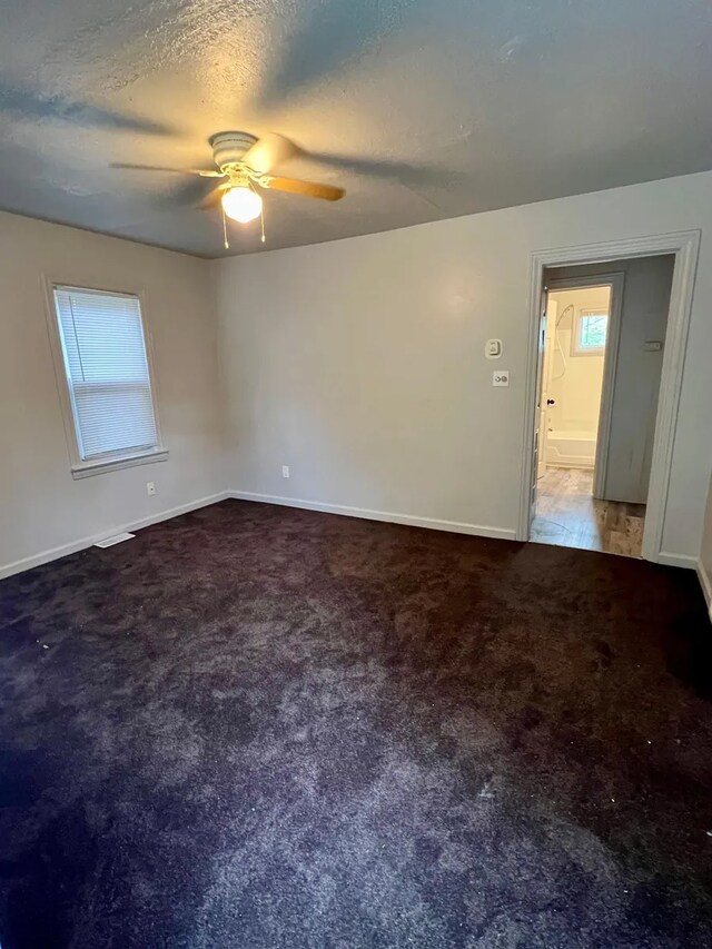 carpeted empty room with ceiling fan and a textured ceiling