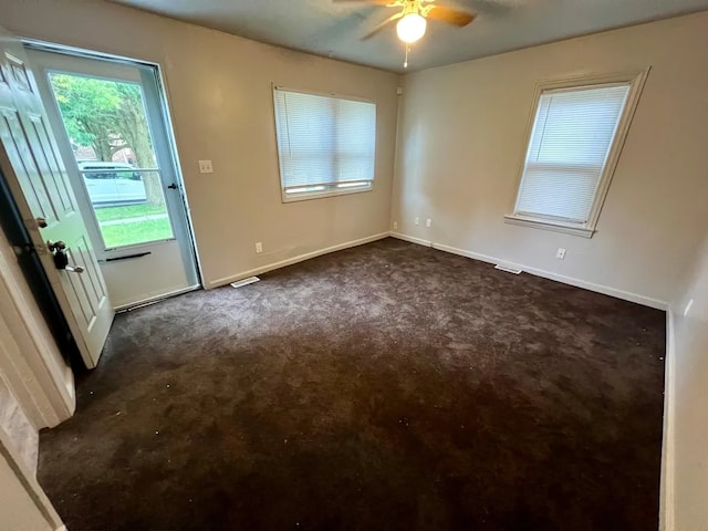 unfurnished room with ceiling fan and dark carpet